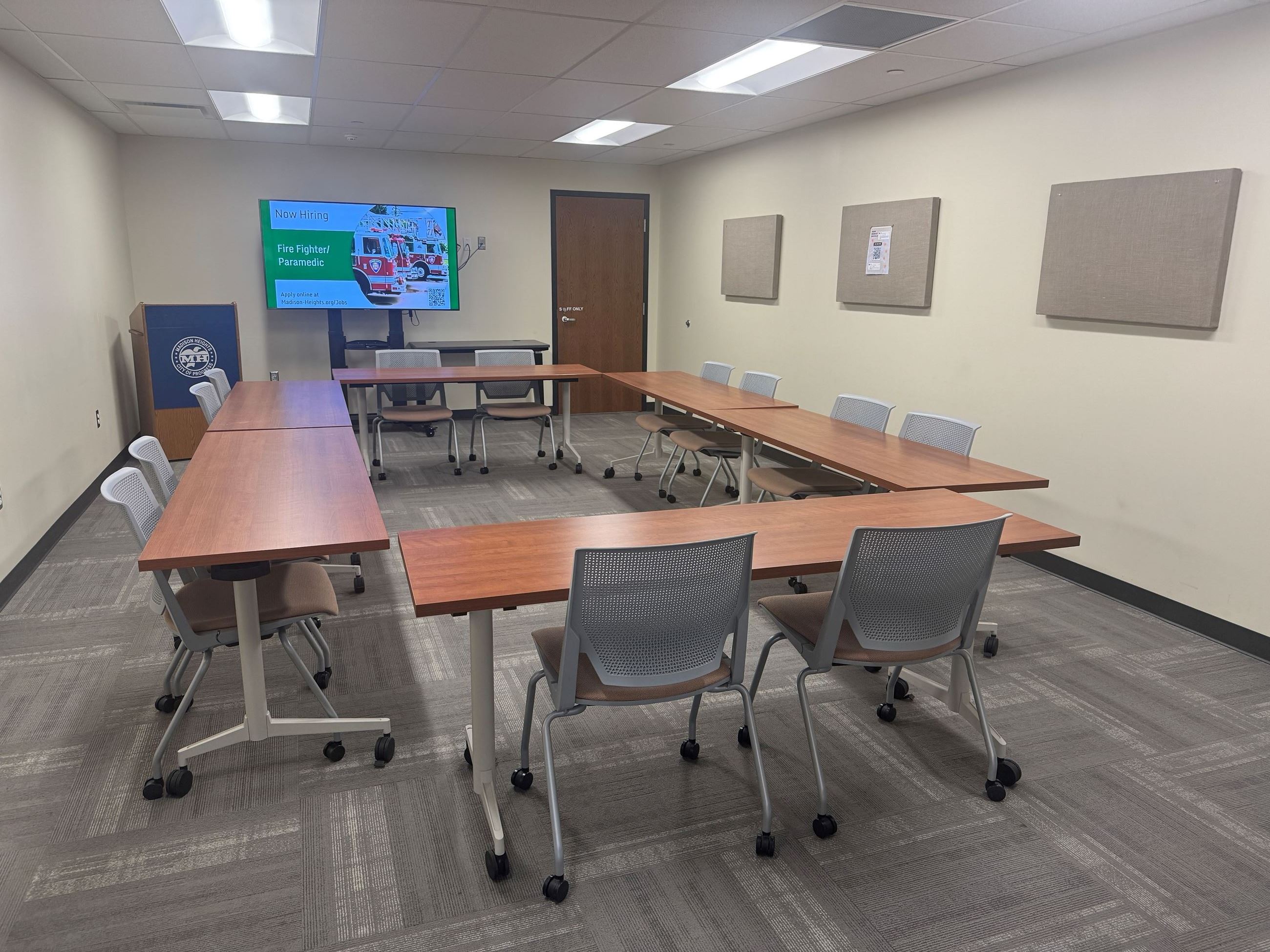 Flex Space with 6 tables and 12 chairs, television screen, and podium