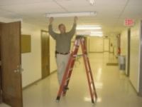 Photo of a man on a ladder fixing a ceiling tile