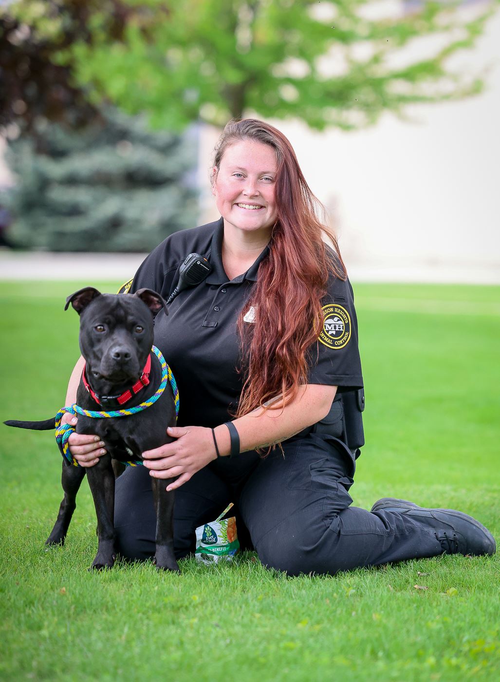 Photo of Paige Wallace sitting  on grass with a black dog next to her